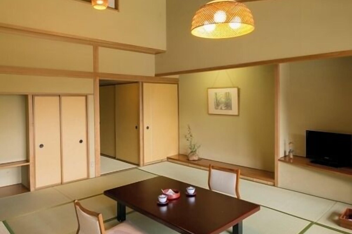 A traditional Japanese-style room with tatami flooring, a low wooden table, and a hanging light fixture.