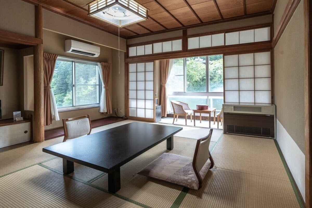 A traditional Japanese room with tatami flooring, a low table, chairs, and sliding doors.