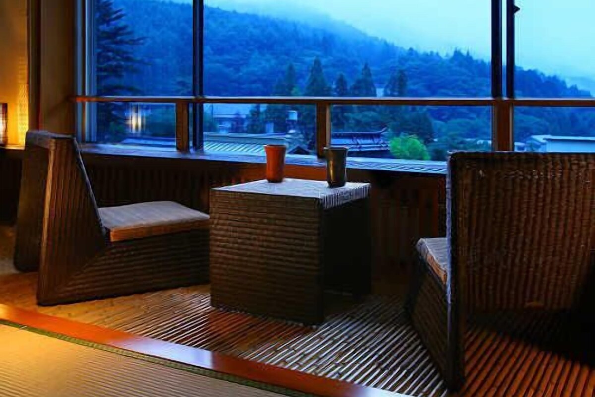 A room with large windows, a cushioned bench, and a small table.