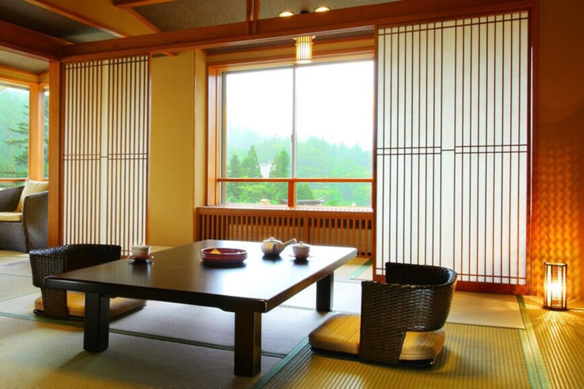 A traditional Japanese room with tatami flooring, a low table, and sliding doors.