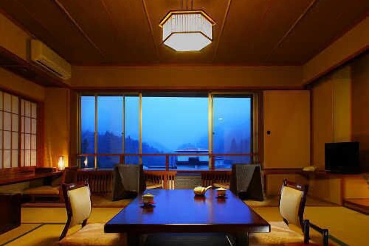 A traditional Japanese room with tatami flooring, a low table, and a view of the mountains.