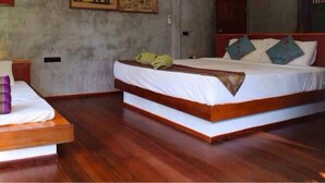 Ein Schlafzimmer mit zwei Betten, Holzboden und einer schlichten Wand mit einem kleinen Bild.