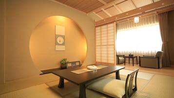 Una habitación tradicional japonesa con suelo de tatami, una mesa baja y un sofá.