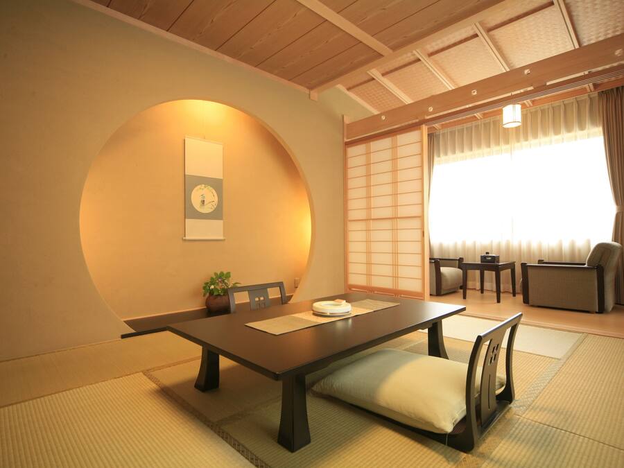 Perinteinen japanilaistyylinen huone, jossa on tatamimatto, matala pöytä ja sohva.