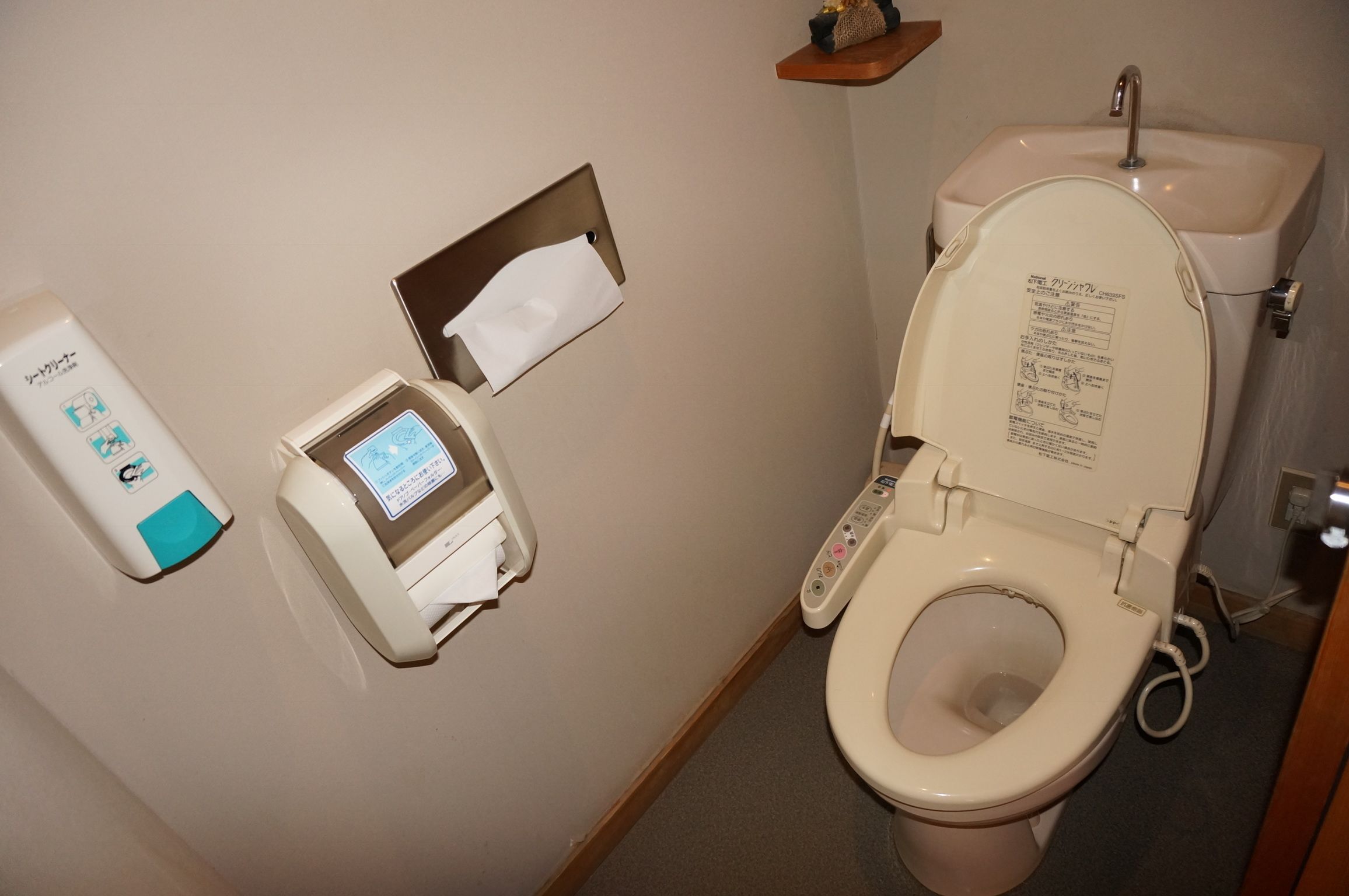 Ett badrum med en toalett, en pappershandduksdispenser och en tvåldispenser.