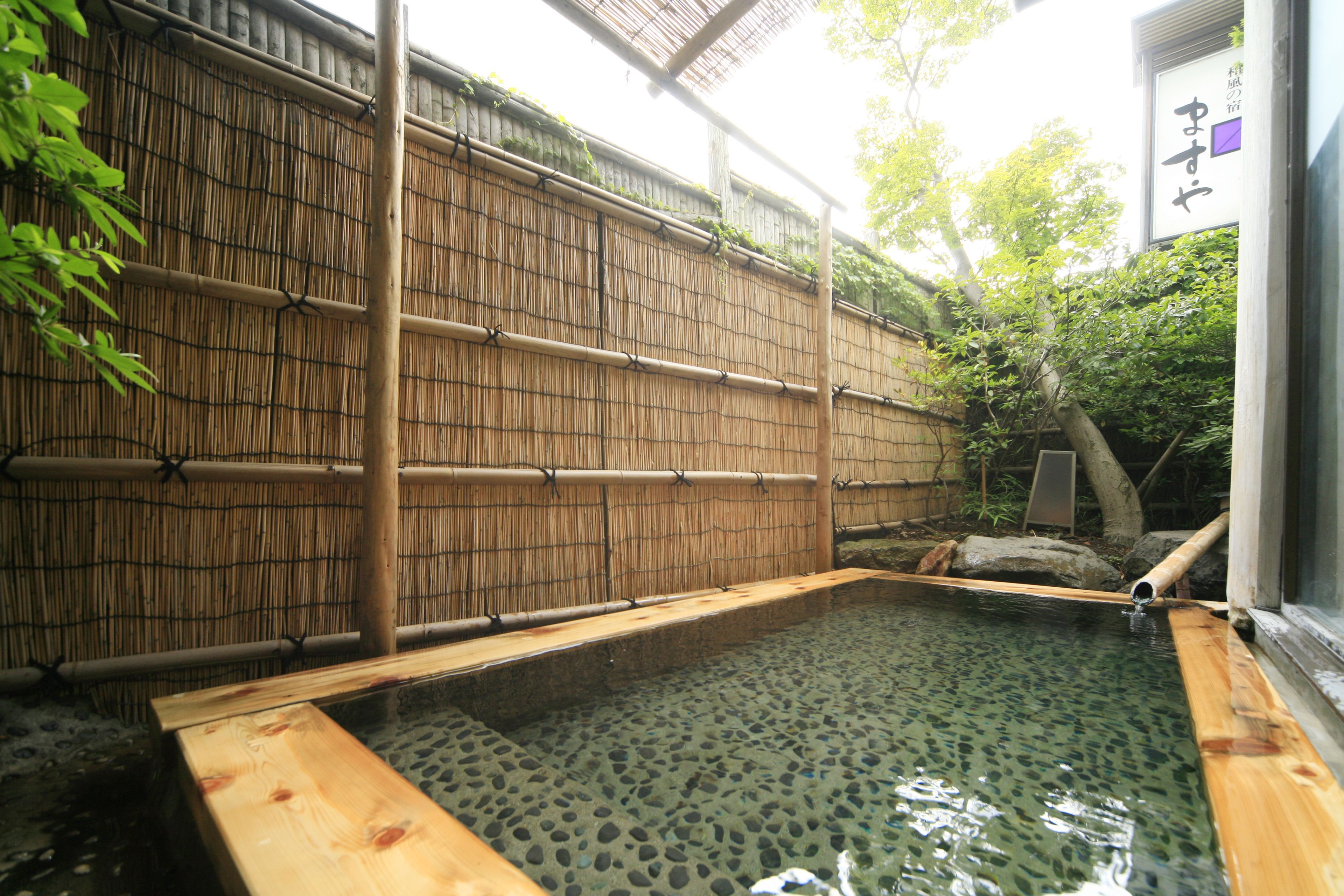 Uma onsen japonesa tradicional com um deque de madeira e parede de bambu.
