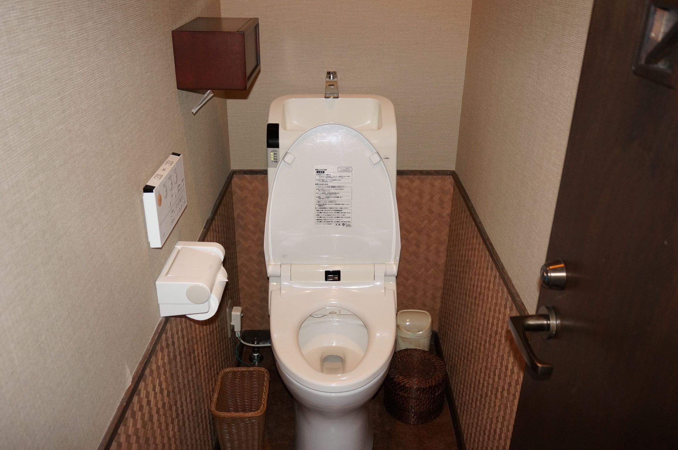 Un baño pequeño con inodoro, secador de manos y dispensador de toallas de papel.