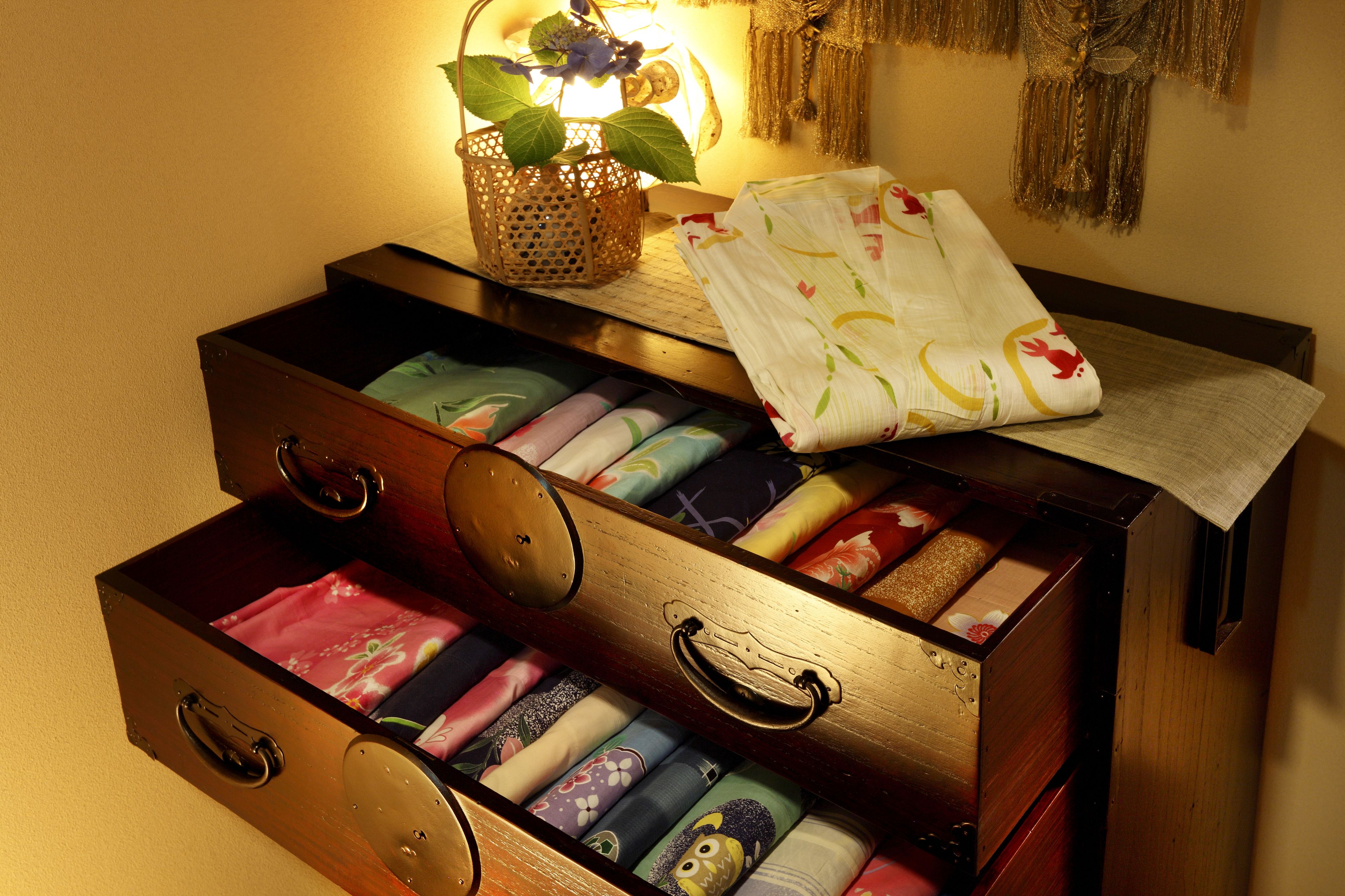 A wooden chest of drawers with colorful fabrics inside.