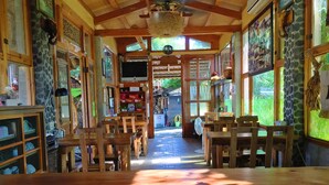 Un restaurant à l’ambiance chaleureuse, avec des meubles en bois, des murs en pierre et de grandes fenêtres.