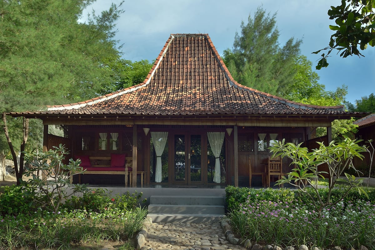 A traditional house with a tiled roof, wooden porch, and steps leading to the entrance.