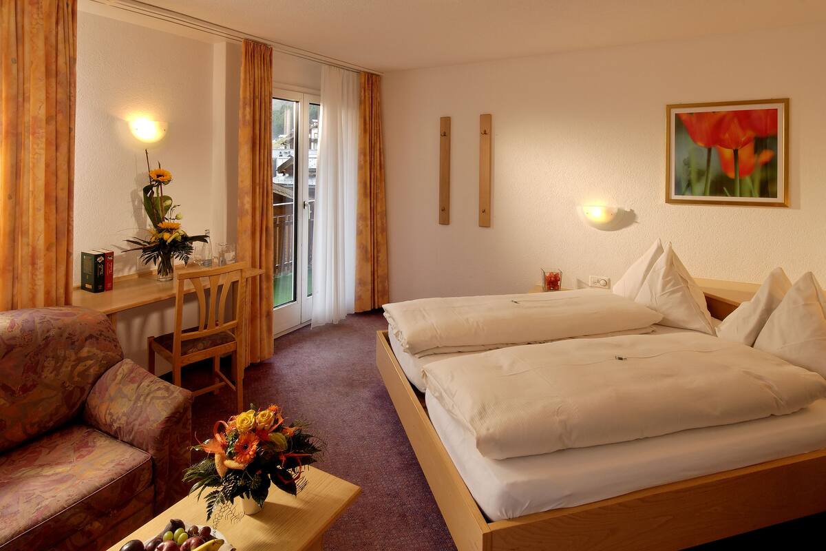 A hotel room with a bed, a sofa, a desk, and a chair.