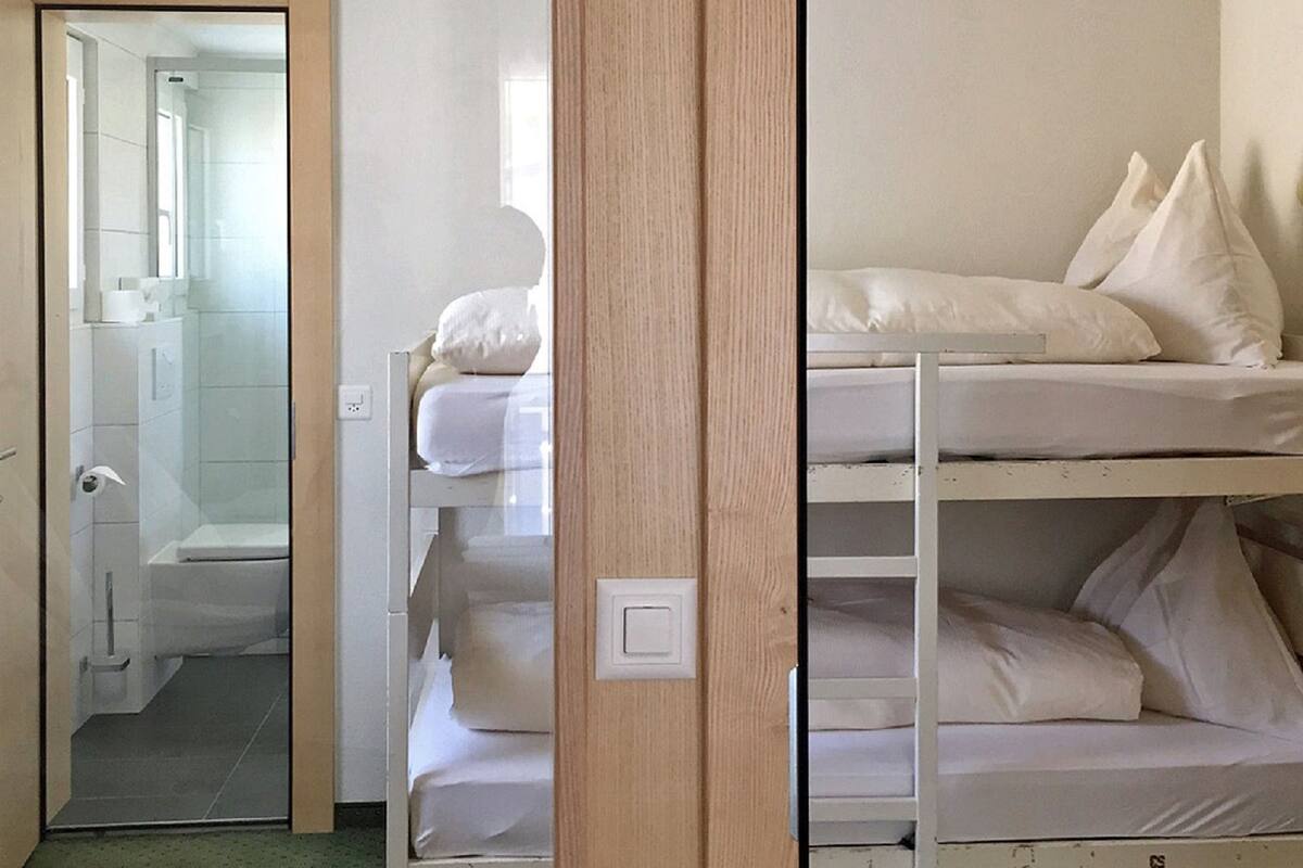 A room with bunk beds, a wooden door, and a bathroom visible through an open door.