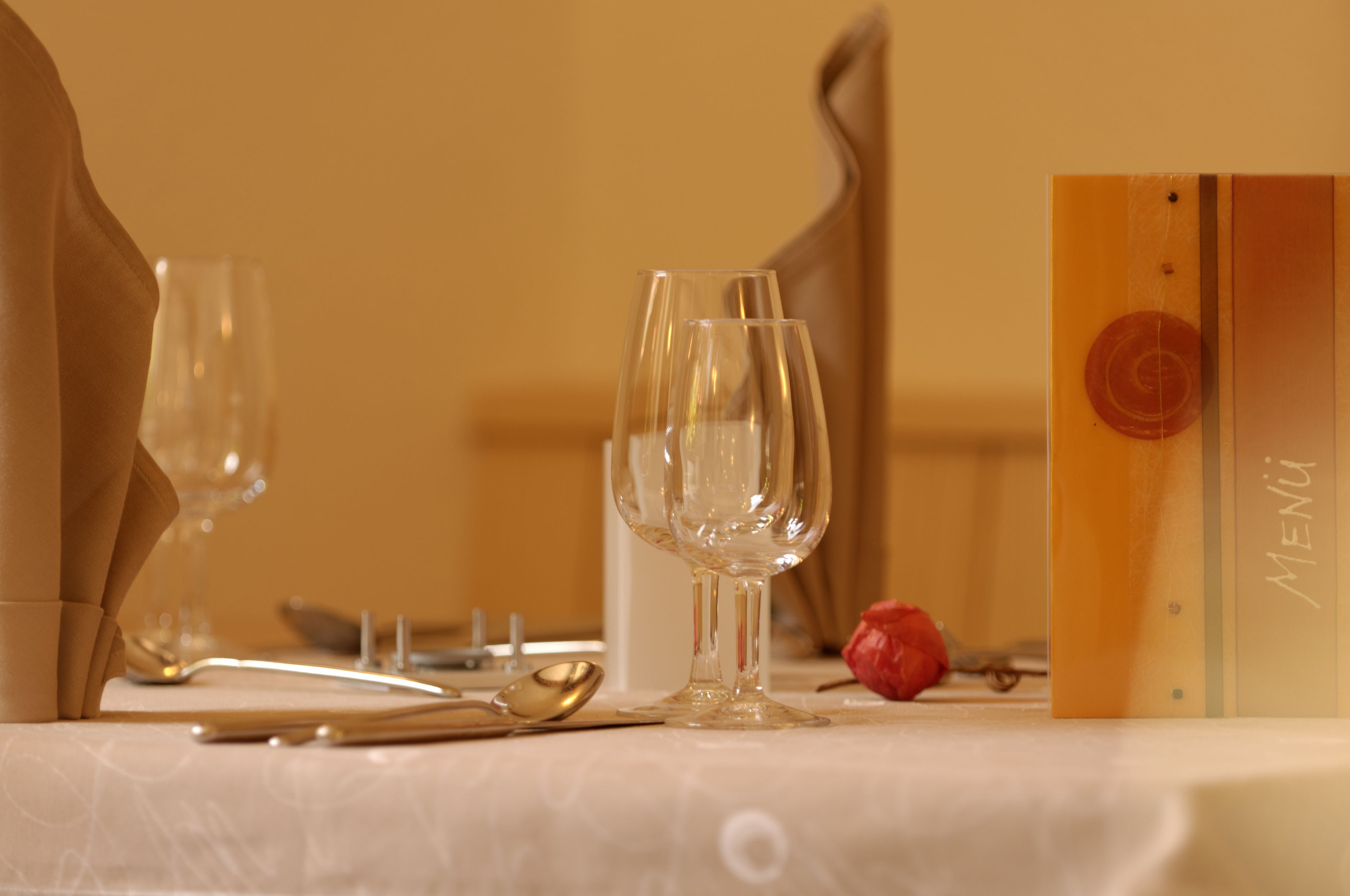 A table set with wine glasses, cutlery, and a menu.