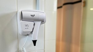 Un sèche-cheveux fixé sur un mur recouvert de carreaux.