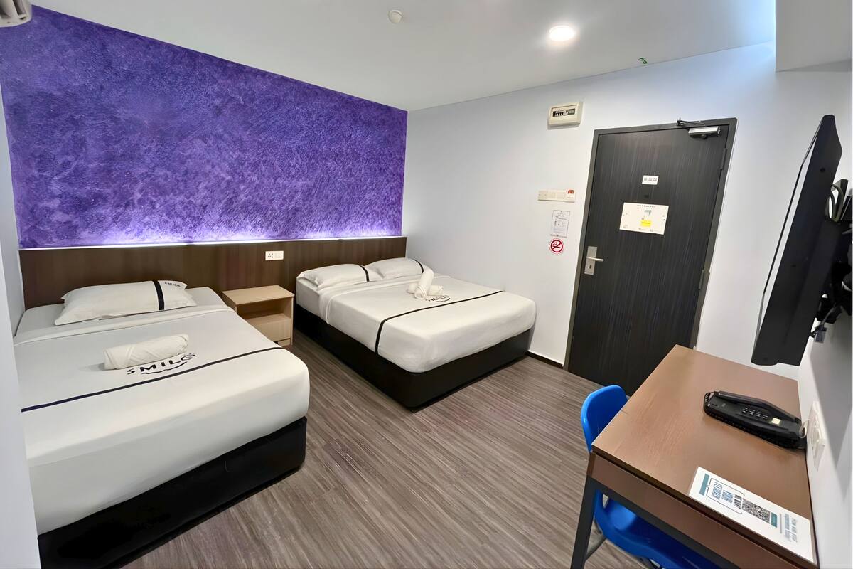 Een hotelkamer met twee bedden, een bureau, een stoel, een televisie en een deur.