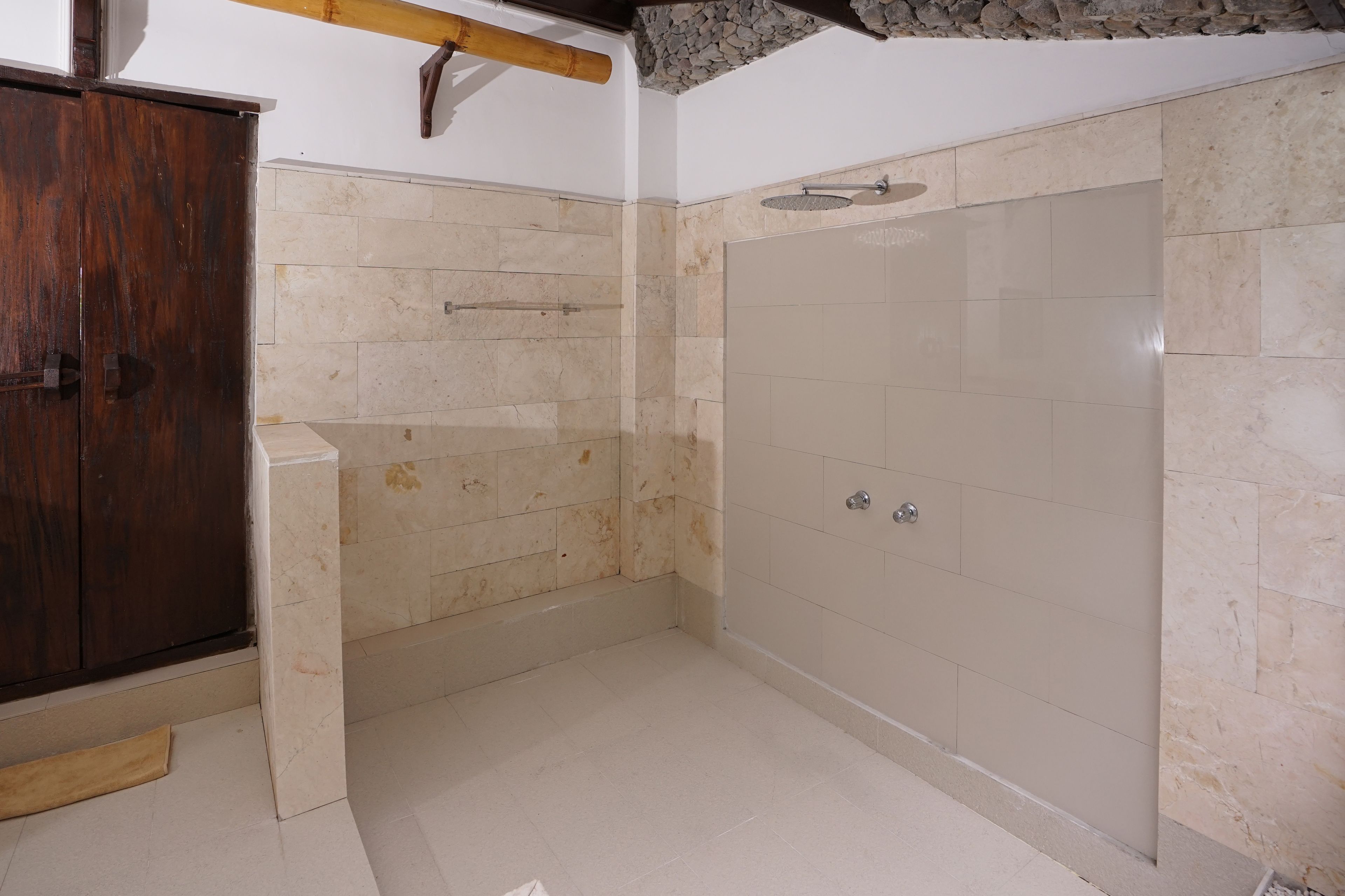 A bathroom with a shower, tiled walls, and a wooden cabinet.