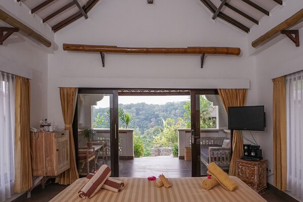 A hotel room with a bed, a TV, a desk, and a view of the mountains.
