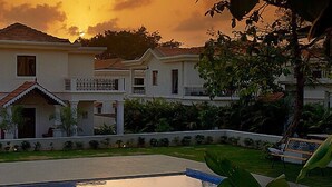 A two-story house with a balcony, surrounded by greenery and a swimming pool. - Pinto Rosario Square Resort and Spa (Guirim)