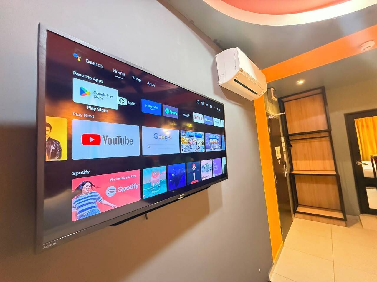 A flat-screen TV mounted on a wall displaying various streaming apps.