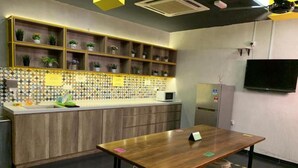 Une cuisine moderne avec un plan de travail en bois, des étagères intégrées ornées de plantes, un four à micro-ondes et un réfrigérateur.