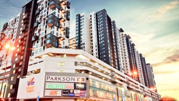 Un immeuble à plusieurs étages doté d’une architecture moderne, avec une enseigne bien visible de « Parkson » et « Econsave » au rez-de-chaussée.
