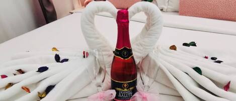 A bed with a bottle of champagne in the center, surrounded by white towels shaped like swans.