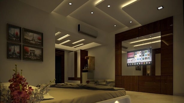 A modern bedroom with a bed, a bedside table, a wall-mounted TV, and a ceiling with recessed lighting. - Rezo's Hotel (Baga)