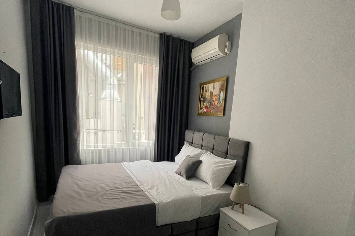 A modern bedroom with a bed, bedside table, and a hanging light fixture.