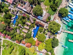 Vue aérienne d’un village côtier avec des maisons, une piscine et des bateaux.
