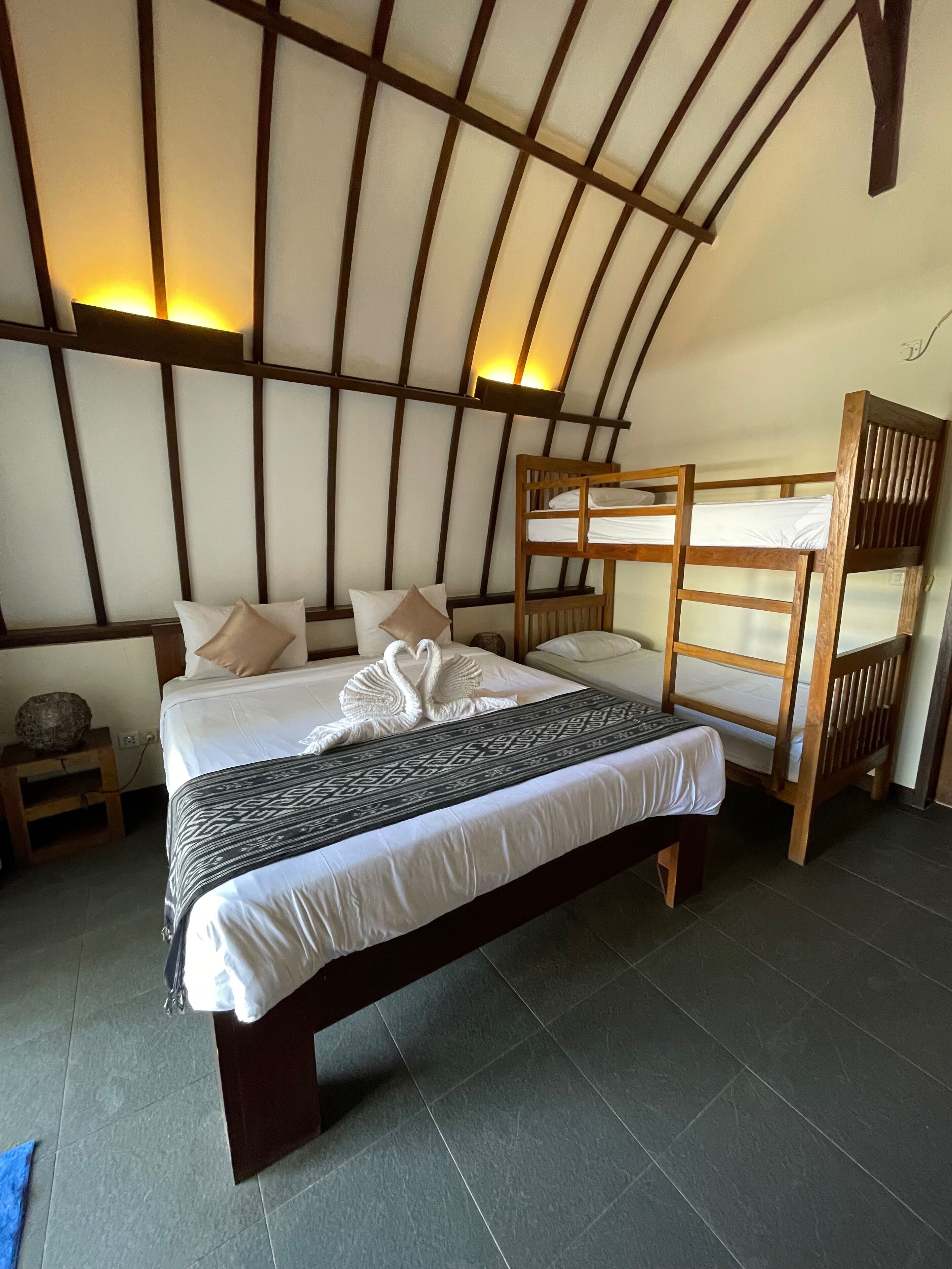 Una habitación con una cama litera, una cama grande con una colcha estampada y un diseño de listones de madera en la pared.