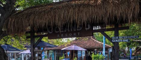 A resort entrance with a thatched roof, a sign reading "OCEANS RESORT," and a blue water express sign.