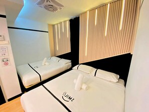 A hotel room with two beds, each with white linens and a smiley face design. There is a ceiling fan, a wall-mounted control panel, and a window with vertical blinds. - Seeds Hotel Setiawangsa (Ampang)