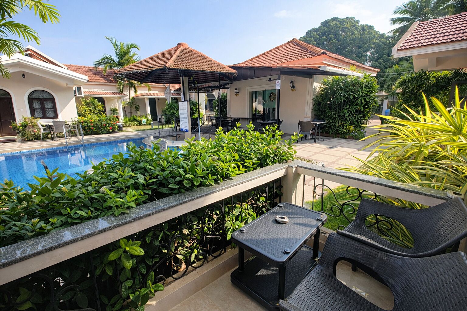 A poolside area with a covered seating area, a table, and chairs.