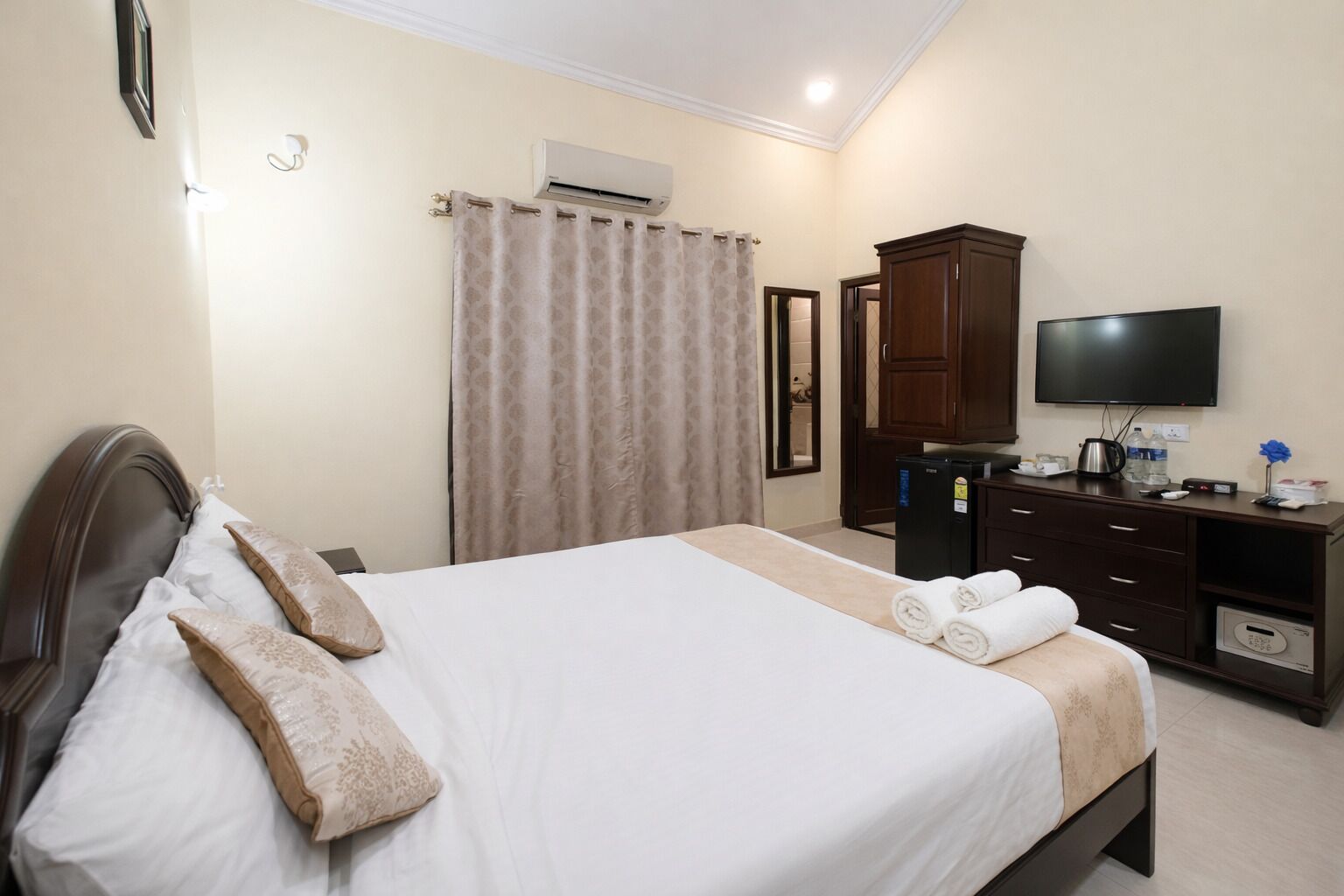 A hotel room with a bed, a television, a desk with a coffee maker, and a wardrobe.