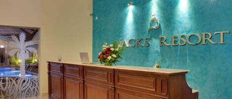 A reception desk at Jack's Resort with a teal wall and a laptop on it.