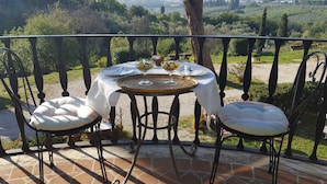 A round table with a white tablecloth, two white cushioned chairs, and a tray with two glasses of a beverage and a small bowl of fruit. - Villa Colle Olivi (Pescia)