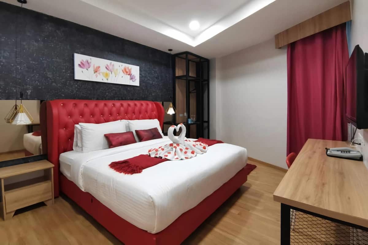 Une chambre moderne avec un lit rouge, une literie blanche et une décoration en forme de cœur.