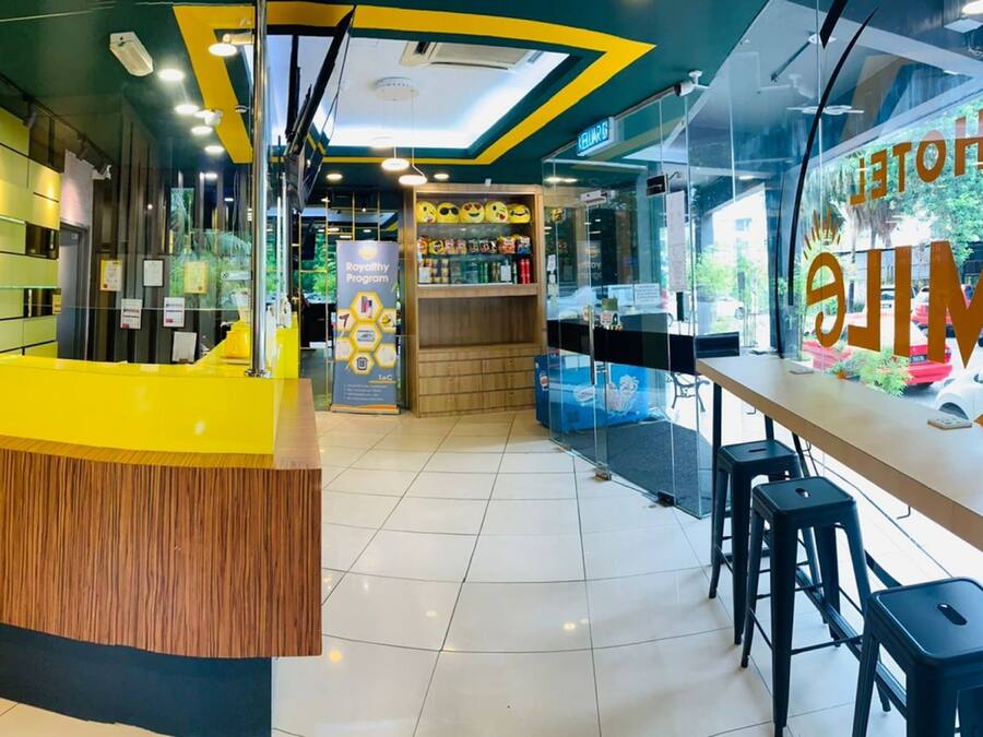 A hotel reception area with a yellow counter, a glass wall with the hotel's name, and a sign for the Royalty Program.