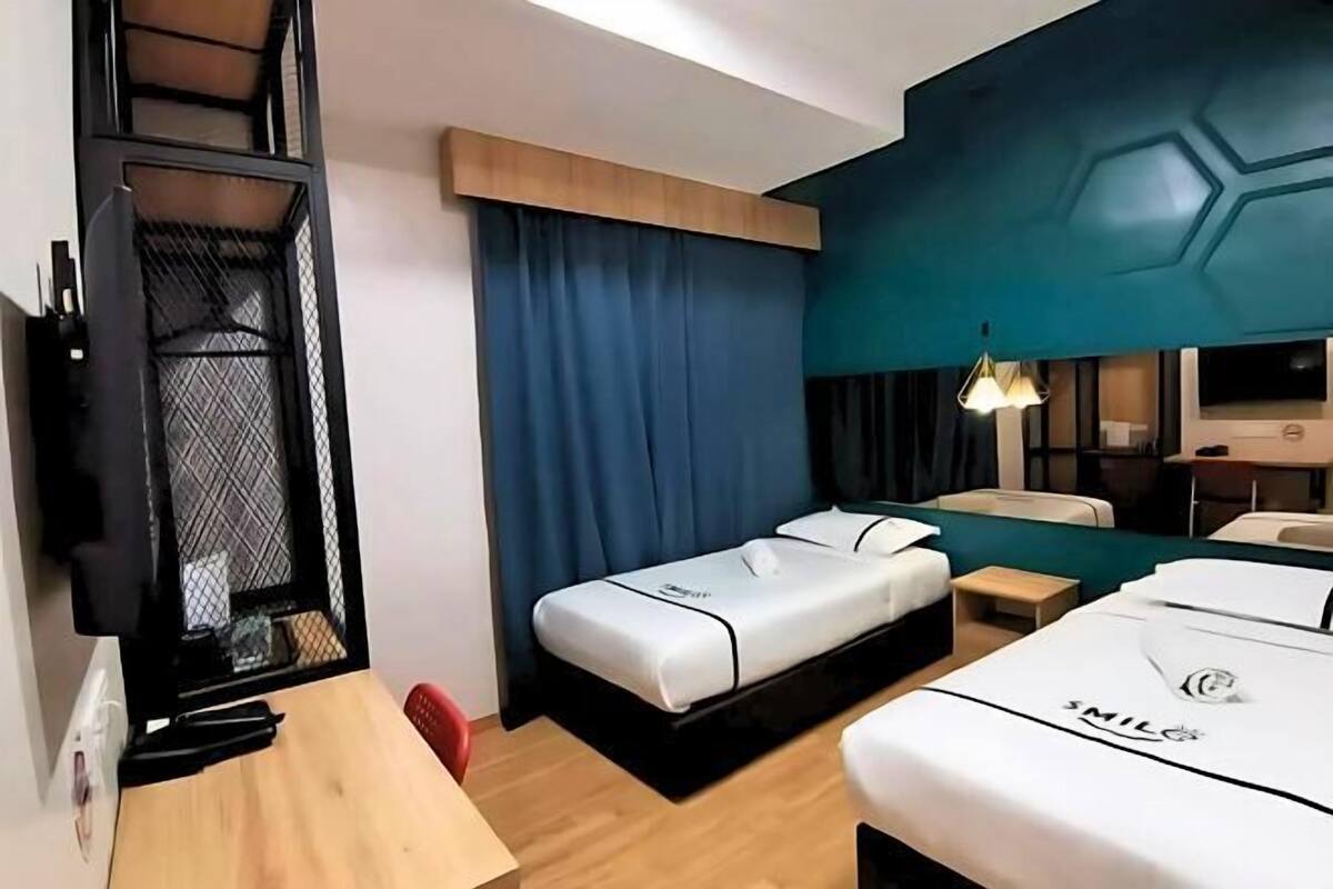 Une chambre d’hôtel avec un lit, un bureau, une télévision et une fenêtre avec des rideaux.