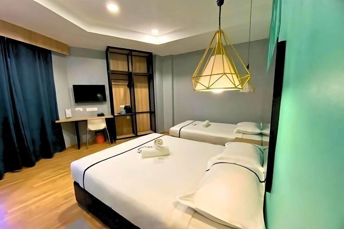 Une chambre d’hôtel comprenant un lit, un bureau avec une chaise, une télévision et un fauteuil massant.