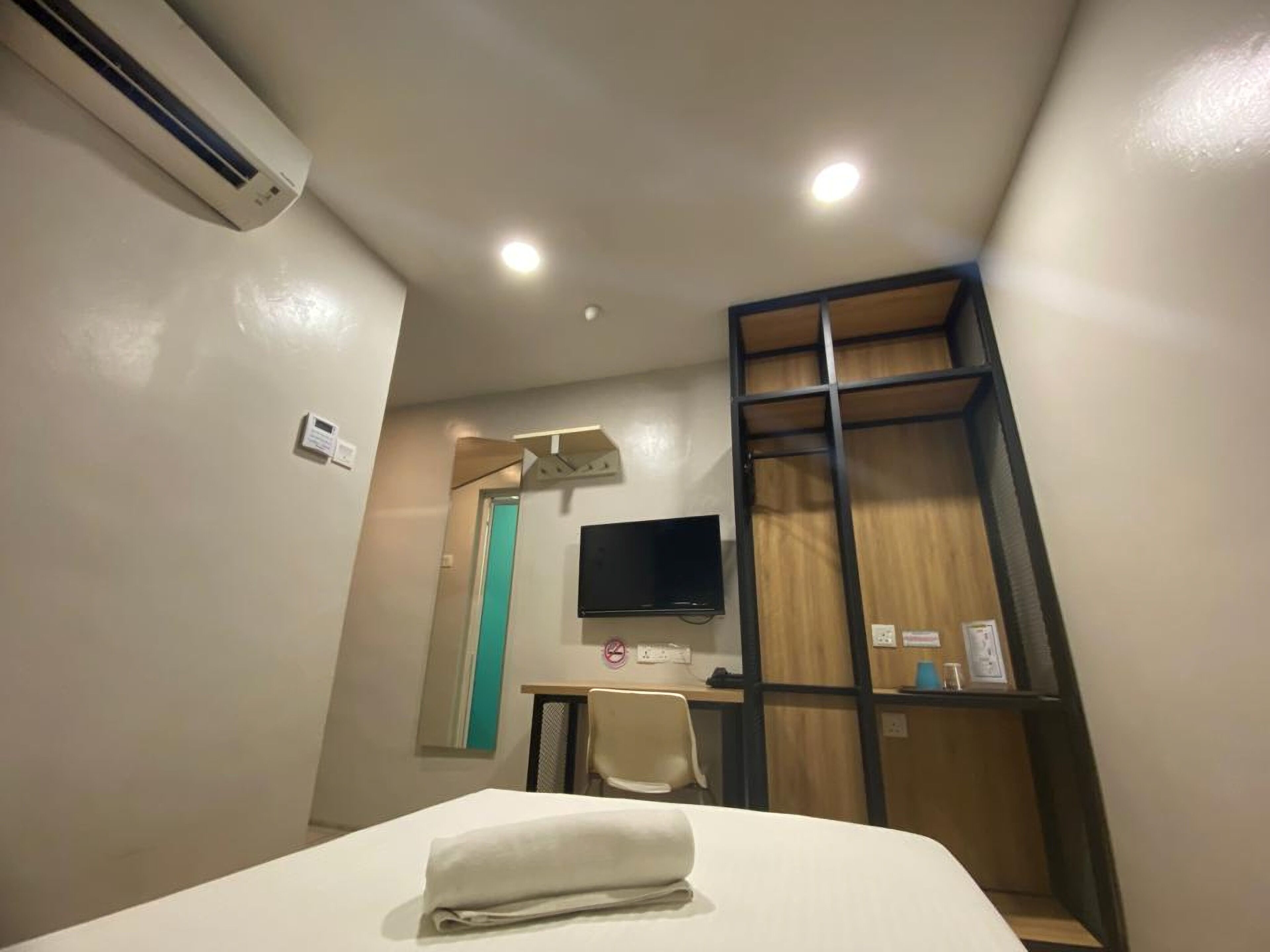 A hotel room with a bed, a desk, a chair, a TV, and a wardrobe.