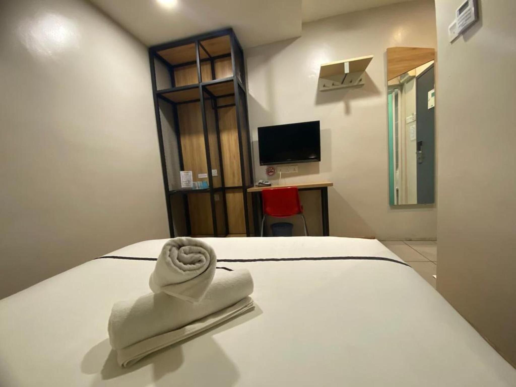 A hotel room with a bed, a desk, a TV, and a wardrobe.