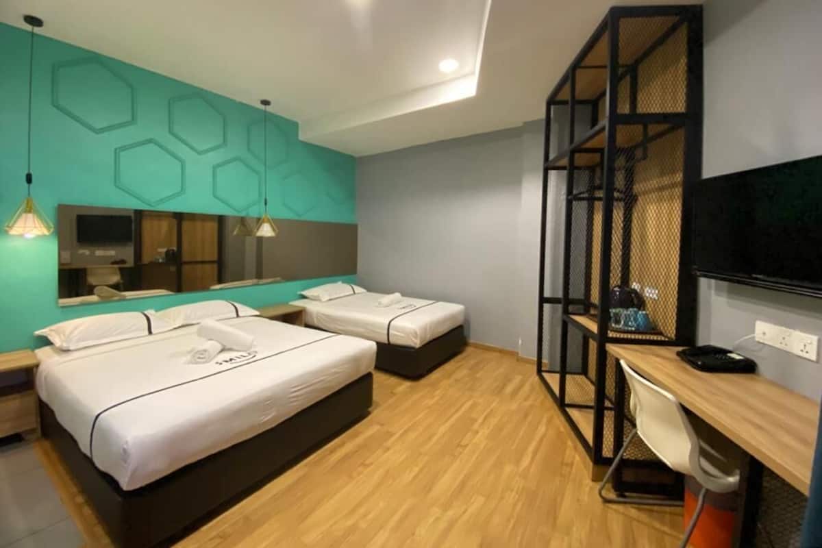 Une chambre d’hôtel moderne équipée de deux lits, d’un bureau, d’une chaise, d’une télévision et d’un grand miroir.