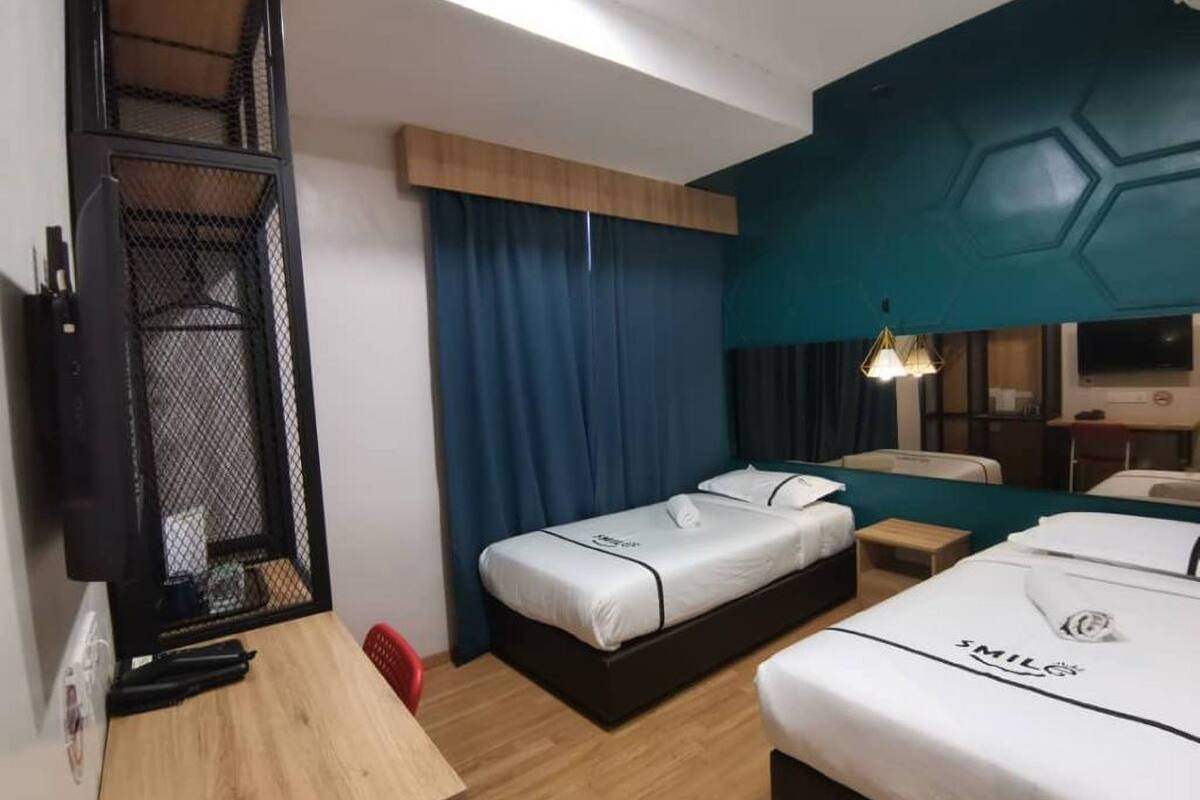 Une chambre d’hôtel avec deux lits, un bureau, une chaise, une télévision et une armoire.