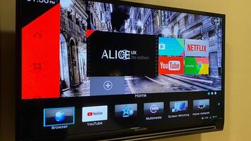 Un televisor mostrando una pantalla de inicio con varios iconos de aplicaciones, incluyendo YouTube y Netflix, y un indicador de tiempo que muestra las 01:56 PM.