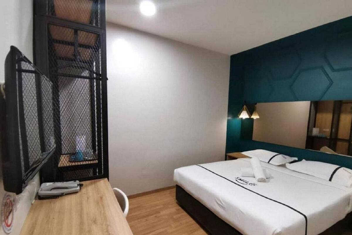 Une chambre d’hôtel équipée d’un lit, d’un bureau, d’une chaise, d’un miroir et d’un téléviseur fixé au mur.