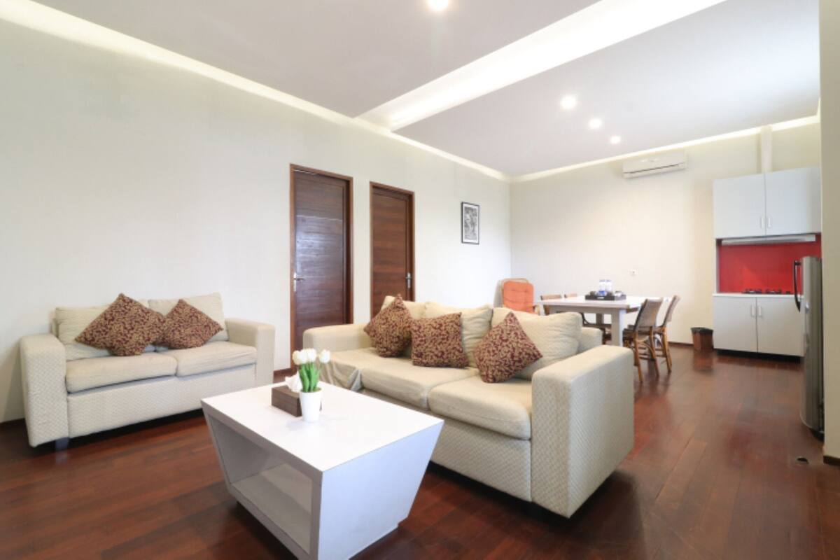 Una sala de estar moderna con dos sofás, una mesa de centro y una zona de comedor con sillas y una mesa.