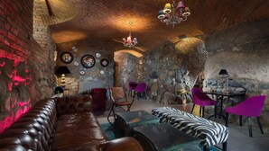 A cozy room with a leather sofa, a zebra-patterned ottoman, and a stone wall.