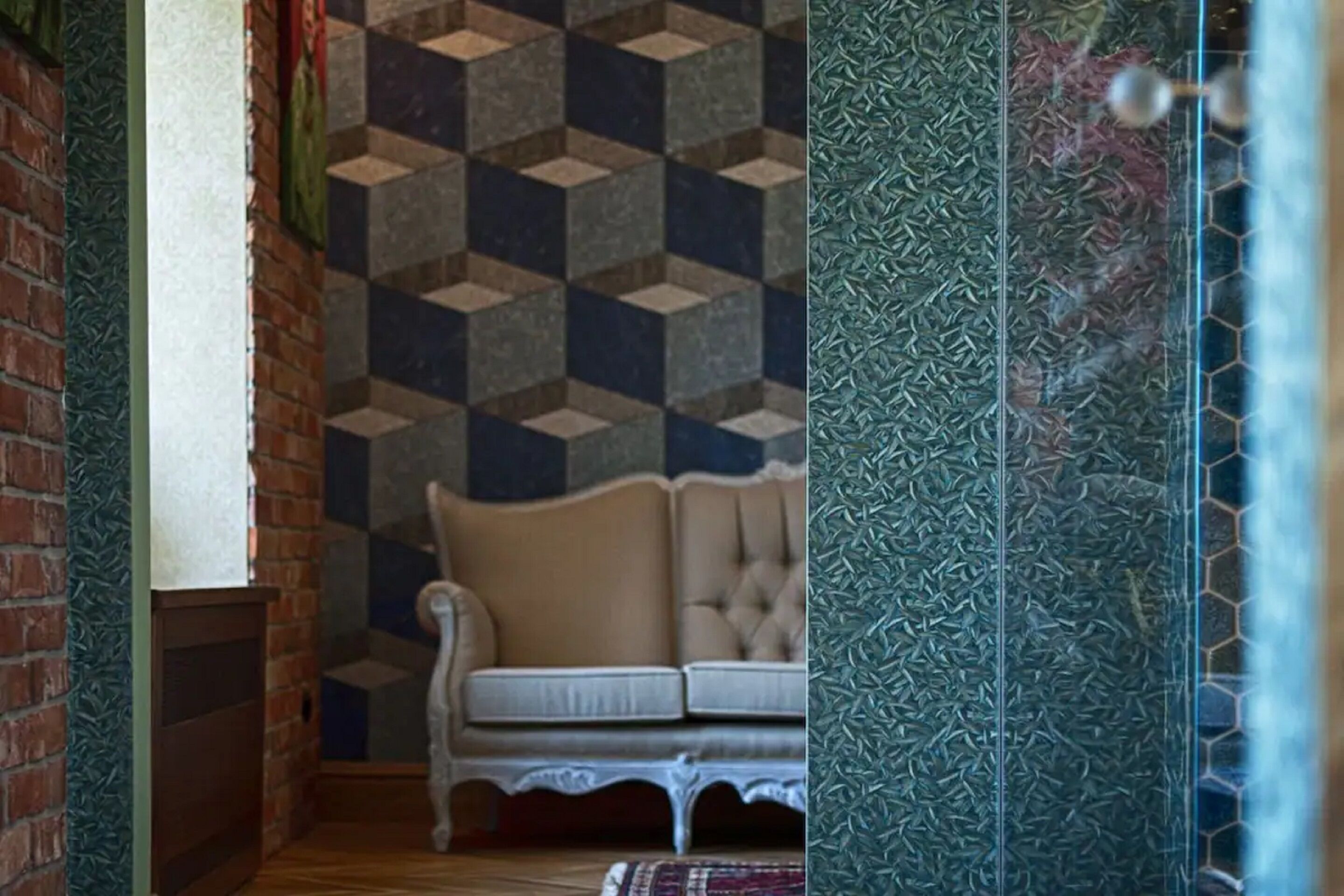 A room with a patterned wall, a white cushioned bench, and a brick wall.