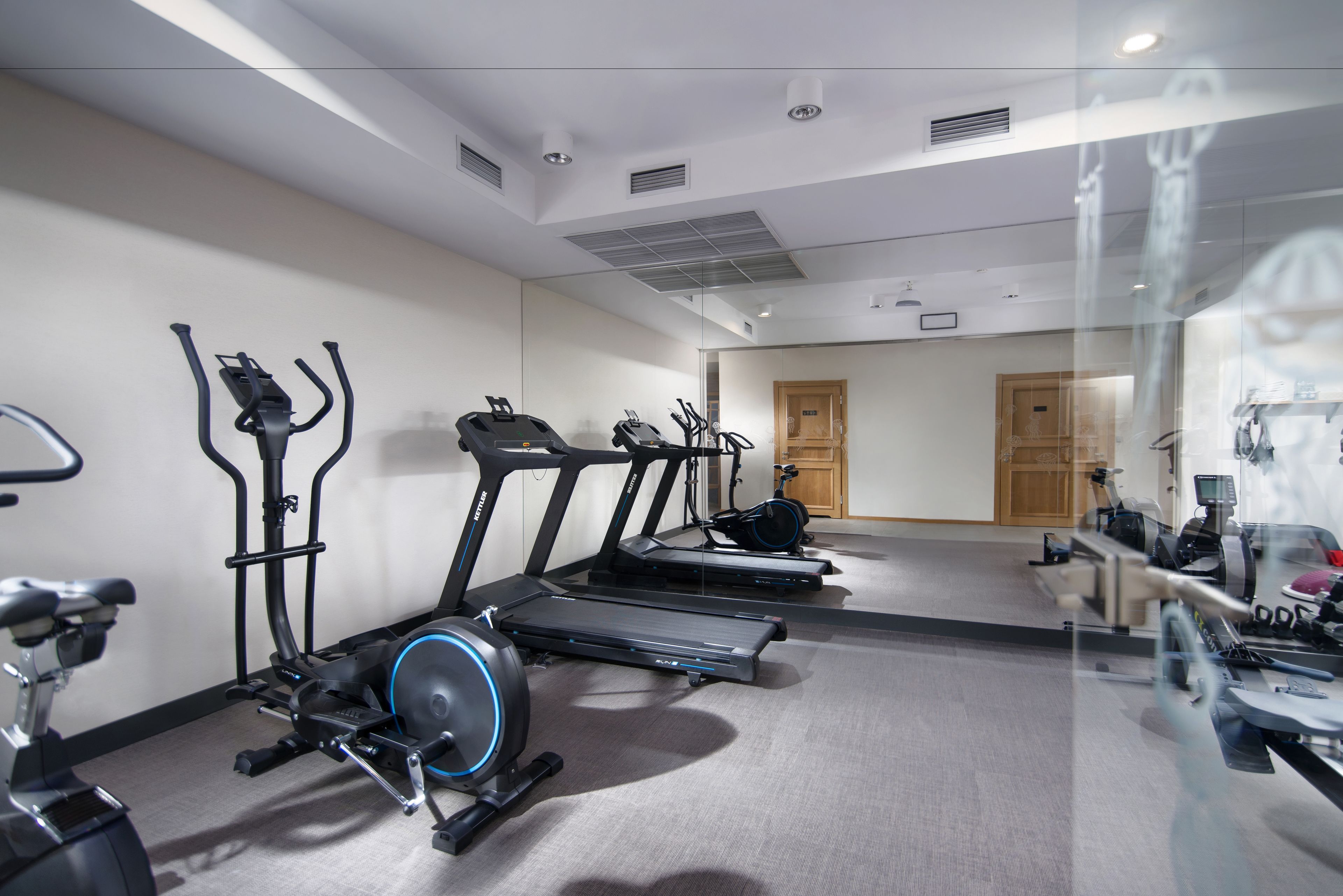 Un gimnasio con cintas de correr, bicicletas estáticas y elípticas.